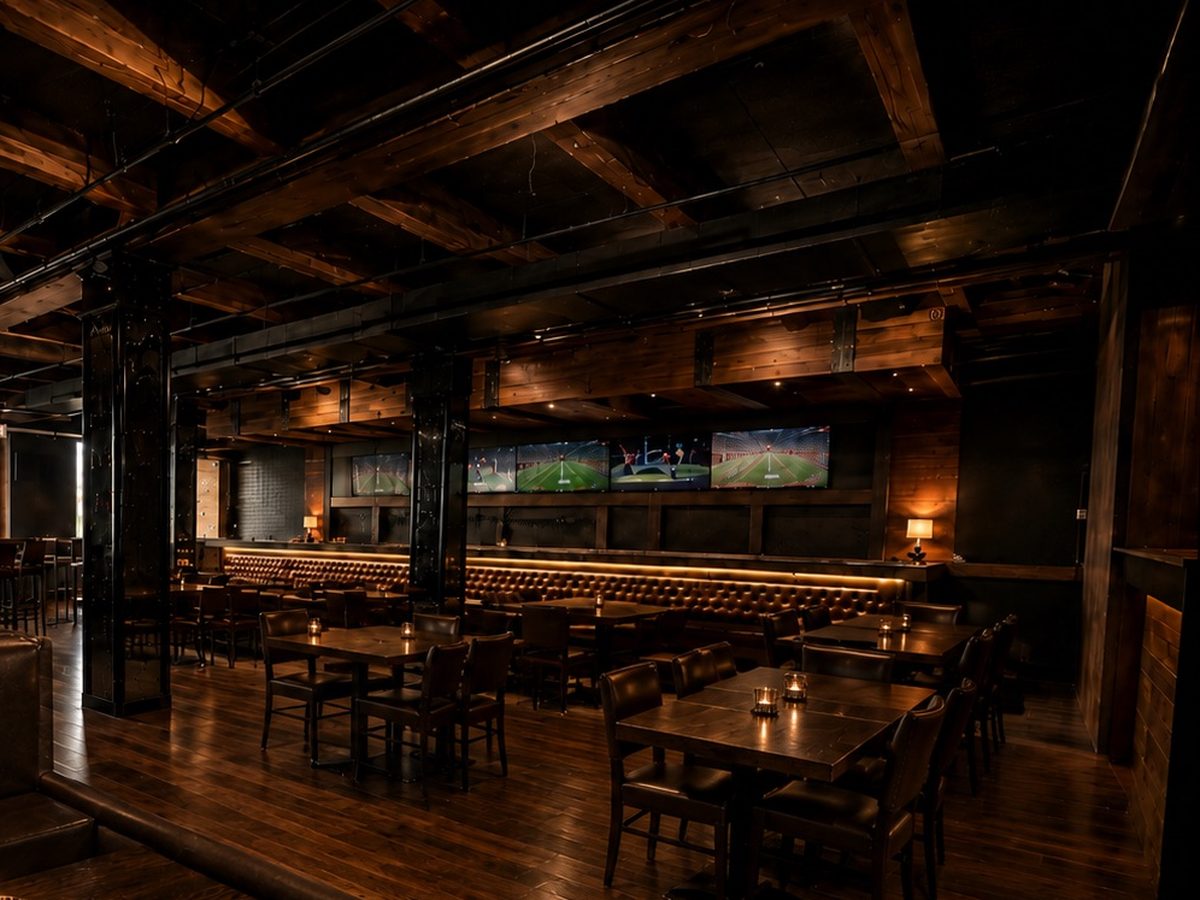The lounge at The Letterman: booths and tables under a row of screens, candles lit, warm light along the banquette.